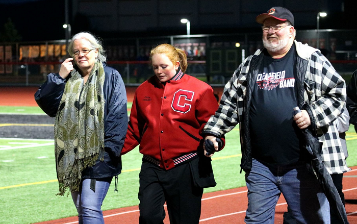 Senior band member, Chloe Brower, walks with her family on Senior Night. 