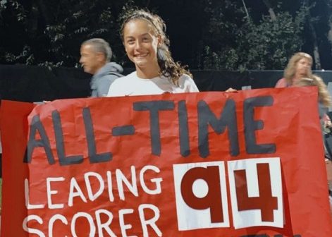 Elle holds the poster that celebrates her record-breaking goal. 