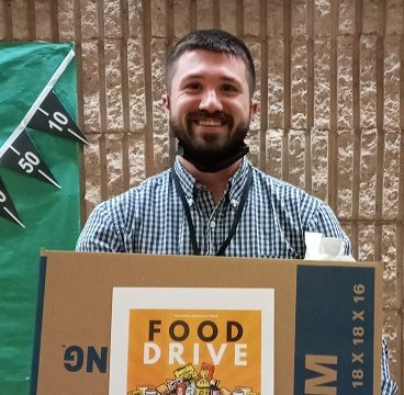 Mr. Bryan, guidance counselor, holding a heavy box of food.